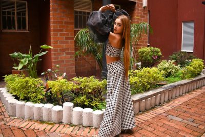 Woman in a chic black and white outfit posing stylishly in a vibrant outdoor setting.